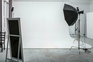 interior do espaço brilhante do estúdio fotográfico com grande ciclorama branco com equipamento de iluminação foto
