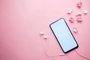 vista superior do smartphone, fone de ouvido e pipoca na cor rosa foto