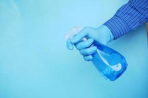 mão com luvas de borracha azuis segurando o spray com espaço de cópia foto