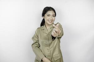 uma jovem ásia mulher dentro Castanho cáqui uniforme mostrando concurso sentindo-me de modelar coração com dela dedos. indonésio governo trabalhador. foto