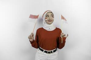 feliz sorridente indonésio muçulmano mulher vestindo vermelho topo e branco hijab segurando da indonésia bandeira para comemoro Indonésia independência dia. isolado de branco fundo. foto