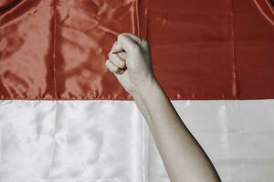 mãos colocar juntos segurando indonésio vermelho e branco bandeira. da indonésia independência dia conceito foto