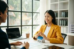 agente imobiliário feminino usa as mãos para proteger o telhado vermelho para o conceito de investimento imobiliário sobre comércio de casas, compra na mesa do escritório foto