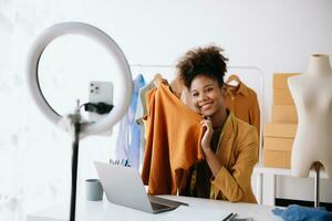 moda blogueiro conceito, jovem africano mulheres vendendo roupas em vídeo streaming.startup pequeno o negócio sme, usando Smartphone ou tábua foto
