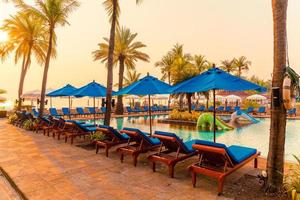lindo guarda-sol e cadeira ao redor da piscina no hotel e resort