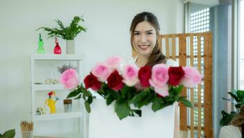 jovem ásia mulher florista trabalhando às flor comprar, ela é feliz e sorridente. entregar flores para clientes foto