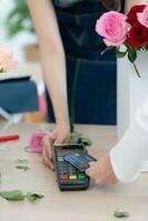 cortada tiro do fêmea florista dando crédito cartão para cliente foto