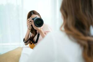 lindo ásia mulher fotógrafo levando cenário com profissional Câmera às casa foto