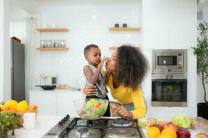 africano americano mãe e filho preparando salada juntos dentro a cozinha às casa foto