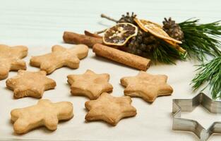 Pão de gengibre biscoitos Como estrelas forma para Natal, em uma de madeira superfície com pinho cones e galhos, seco fatias do laranja e canela Gravetos foto