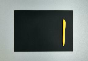 plano deitar composição com amarelo caneta em uma Preto desenhador papel em uma cinzento fundo. topo Visão foto