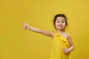 fofa pequeno bebê menina pontos dele dedo certo para a amarelo fundo com cópia de espaço foto