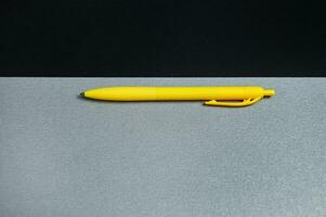 uma parte do Preto Folha do papel e uma amarelo caneta em uma cinzento fundo. plano deitar, topo visualizar, cópia de espaço foto