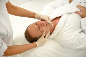 Alto ângulo retrato do bonito Senior homem desfrutando facial massagem às luxo spa Centro, cópia de espaço para anúncio. foto