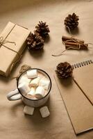 monocromático Castanho colori composição com uma presente caixa dentro construir invólucro papel, canela amarrado com corda, pinho cones, de madeira lápis em bloco de anotações e copo com cacau e marshmallows. Natal decoração. foto