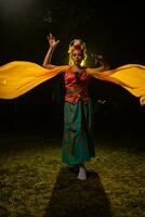uma tradicional indonésio dançarino danças com uma amarelo cachecol este flutua dentro a ar foto