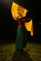 uma tradicional indonésio dançarino danças com uma amarelo cachecol este flutua dentro a ar foto