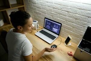 a sobrecarga Visão do uma fêmea médico dentista sentado dentro frente do uma computador portátil com uma panorâmico raio X do a humano dentes e dando conectados consulta para uma paciente de vídeo ligar sobre a dental tratamento foto