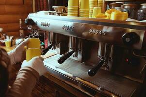 fechar-se do barista mãos dentro luvas segurando amarelo Leve embora papel copos e em pé perto uma profissional café máquina foto