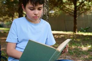 fechar-se do uma Adolescência estudante lendo livro, fazendo dever de casa ao ar livre. pessoas. erudição. Educação. costas para escola foto