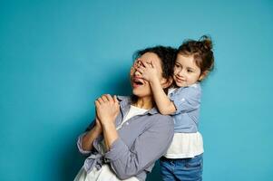 fofa menina abraços dela mãe cobertura dela olhos com dela mãos. emoções. jogar. amor, Cuidado, ternura, feliz infância conceito. foto