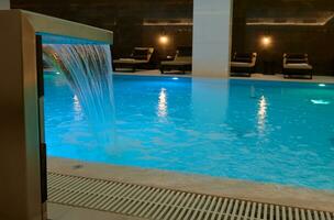 interior térmico natação piscina com cascata e embaixo da agua iluminações dentro uma luxo salão área do uma bem estar spa Centro foto