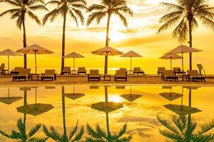 guarda-sol e cadeira ao redor da piscina em hotel resort para viagens de lazer e férias perto da praia do mar foto