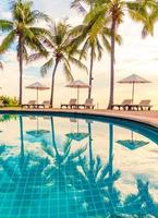 guarda-sol e cadeira ao redor da piscina em hotel resort para viagens de lazer e férias perto da praia do mar