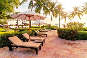 guarda-sol e cadeira ao redor da piscina em hotel resort para viagens de lazer e férias perto da praia do mar