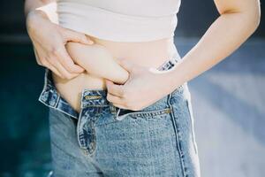 mulher gorda, barriga gorda, gordinha, mão de mulher obesa segurando gordura excessiva da barriga com fita métrica, conceito de estilo de vida de dieta de mulher foto