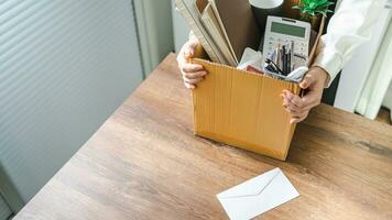 o negócio mulher enviando renúncia carta e embalagem coisa demitir-se deprimir ou carregando o negócio cartão caixa de escrivaninha dentro escritório. mudança do trabalho ou disparamos a partir de companhia foto