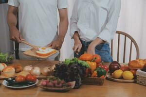 bonito homem sentado perto dele esposa às cozinha. família casal Vejo social meios de comunicação, surfar a rede enquanto sentado às cozinha mesa com genérico computador portátil. casal trabalhando com computador portátil às casa foto