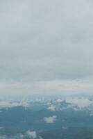 lindo panorâmico Visão do névoa e nuvens dentro distante camadas montanhas alcance com azul céu dentro manhã foto