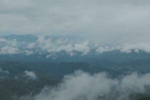 lindo panorâmico Visão do névoa e nuvens dentro distante camadas montanhas alcance com azul céu dentro manhã foto