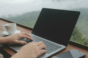 jovem homem trabalhador autonomo viajante vestindo chapéu qualquer lugar trabalhando conectados usando computador portátil e desfrutando montanhas Visão foto