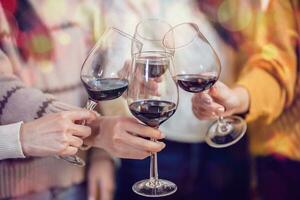 alegre amigos desfrutando casa aniversário feriado Festa. ásia amigos torcendo bebendo vermelho vinho a comemorar Natal ou Novo ano festa foto