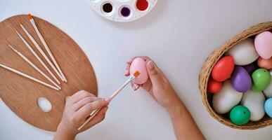 mulher pintura Páscoa ovos às lar. família preparando para Páscoa. mãos do uma menina com uma Páscoa ovo foto