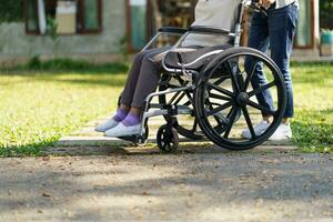 enfermagem lar. jovem cuidador ajudando Senior mulher dentro cadeira de rodas. foto