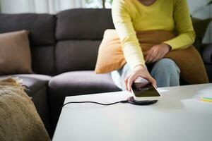 cobrando Móvel telefone bateria com sem fio cobrando dispositivo dentro a mesa. Smartphone cobrando em uma cobrando almofada. Móvel telefone perto sem fio carregador moderno estilo de vida tecnologia conceito. foto