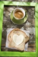 uma coração em forma pão e uma copo do café foto