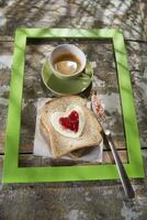 uma coração em forma sanduíche em uma prato com uma copo do café foto