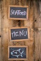 três quadros negros com a palavras frutos do mar cardápio e peixe em eles foto