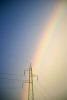 Alto tensão e arco Iris postes foto