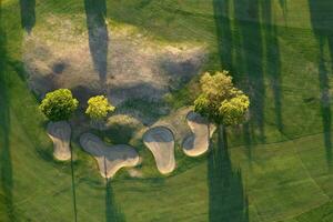 aéreo Visão do uma verde golfe curso às pôr do sol foto