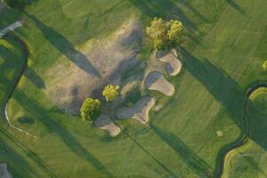 aéreo Visão do uma verde golfe curso às pôr do sol foto