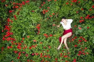 aéreo tiro do uma menina deitado dentro uma papoula campo foto