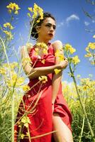 jovem menina vestido dentro vermelho dentro uma campo do amarelo flores foto