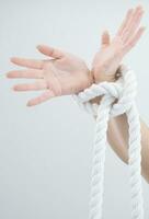 uma mulher mãos estão amarrado para uma corda foto
