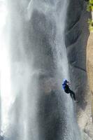 uma pessoa em uma corda escalada acima uma cascata foto