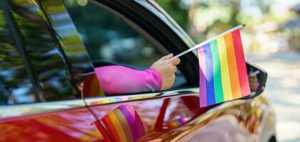 feliz ásia mulher Apoio, suporte lgbt orgulho parada dentro carro. com arco Iris do lgbtq ou lgbtqia. foto